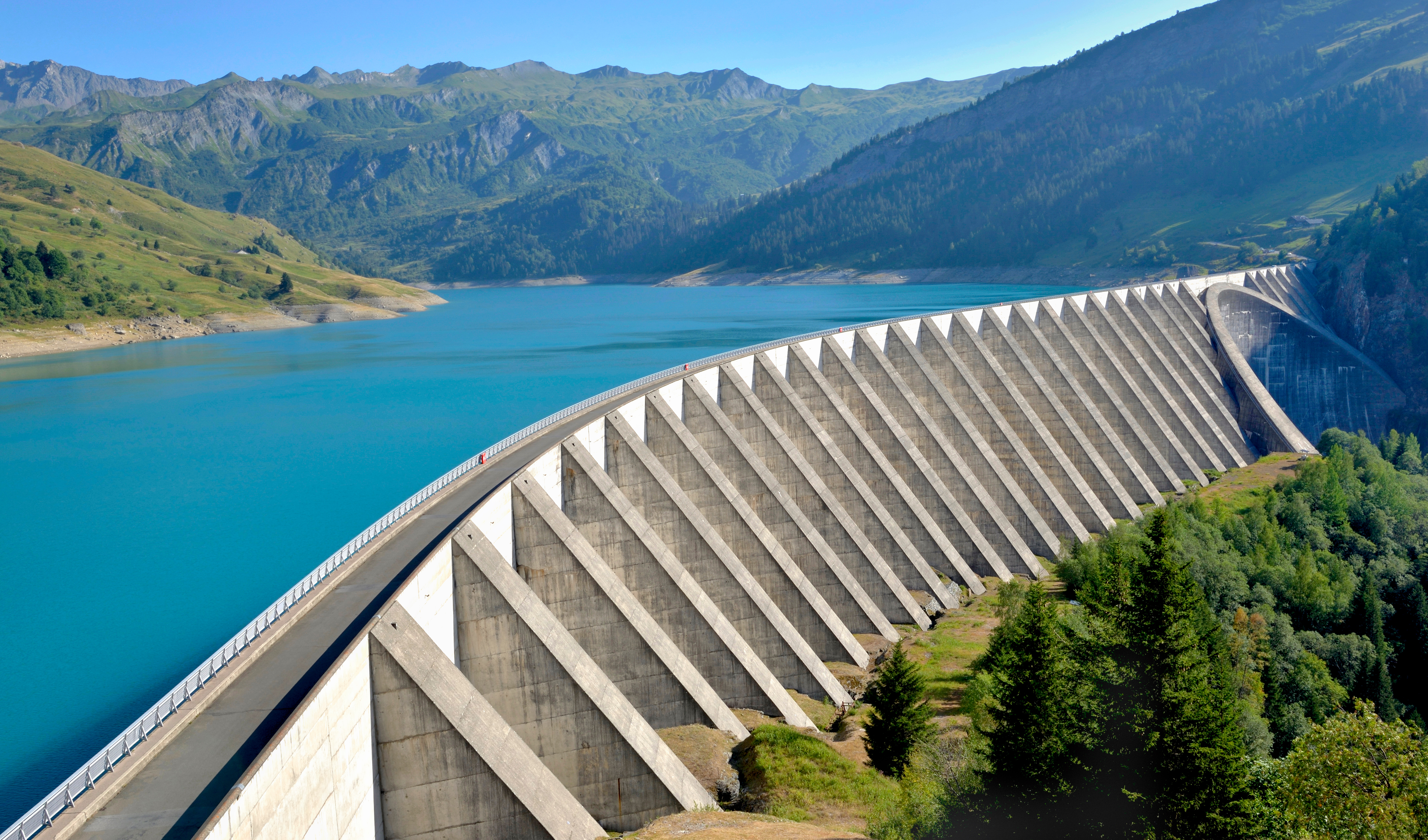 Hydroelectric concrete dam surrounded by mountains and reservoir